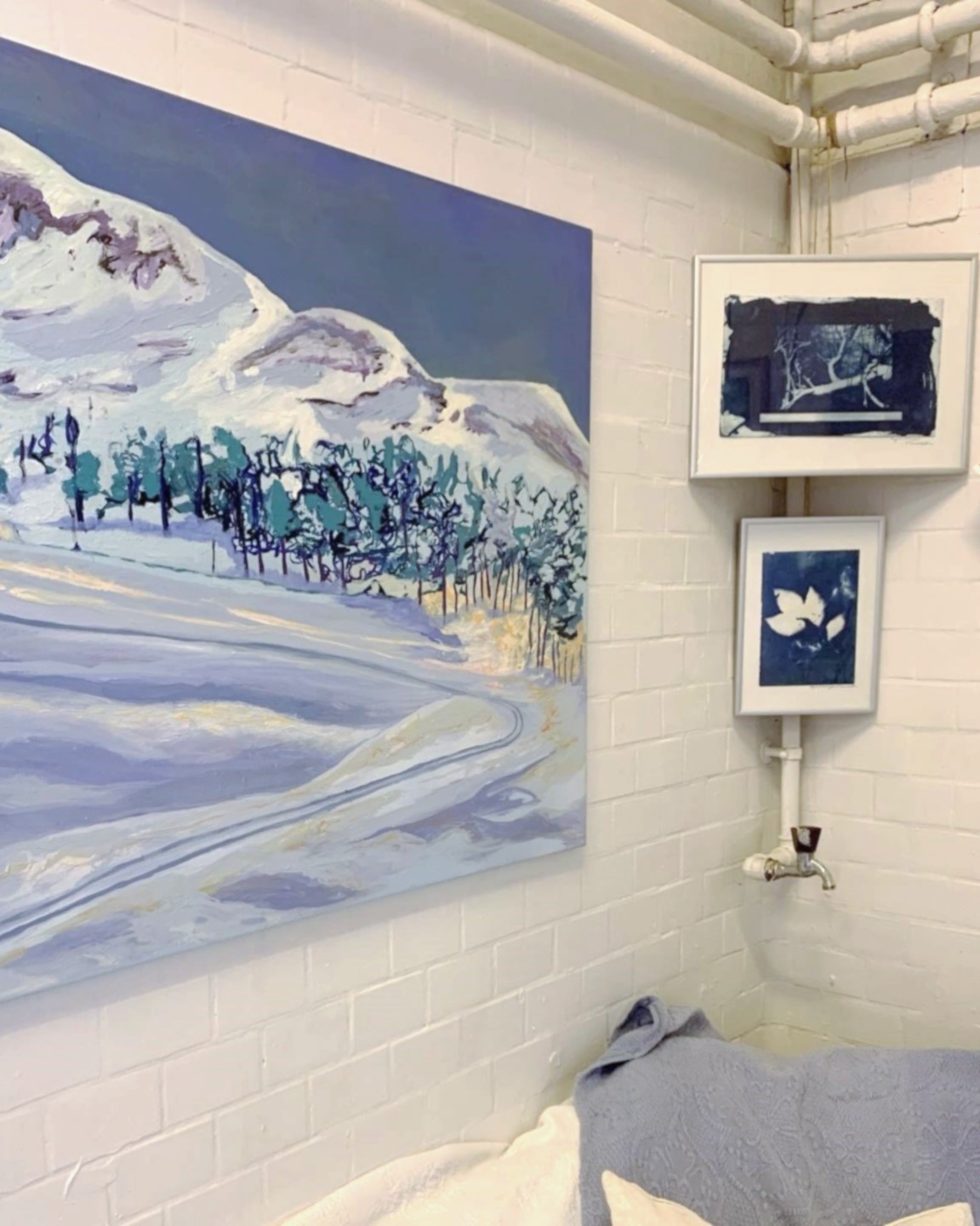 Smukke malerier i blå nuancer på væggene i udstillingen i værkstedet/atelieret